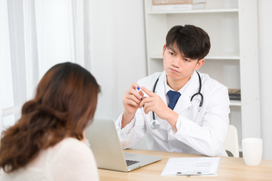 坐在办公室里的亚洲男医生正在询问患者的病情