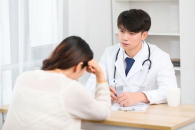 坐在办公室里的亚洲男医生正在询问患者的病情