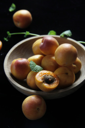 黑色背景下弱光盘子里多个小红杏特写场景