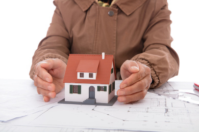 老人双手呵护着图纸上的房子模型