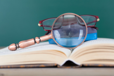 打开的书本上放着放大镜和黑板擦及一副眼镜