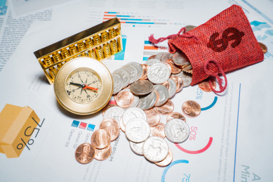 金融经济图表报表上放着硬币金币和指南针投资方向概念