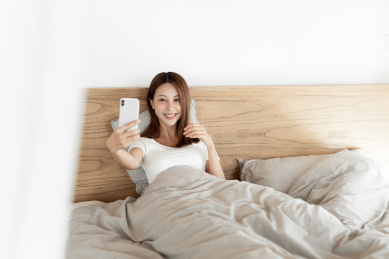 一位年轻女性在床上使用手机自拍