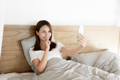 一位年轻女性在床上使用手机自拍