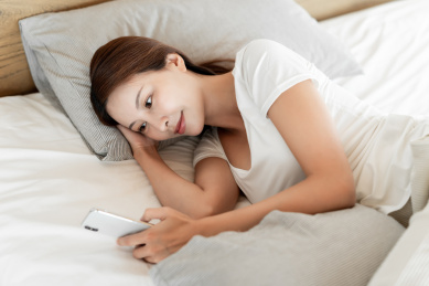 一位年轻女性躺在床上使用手机