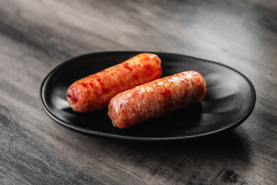 棕色木纹桌面上的盘子里放着两根烤肠
