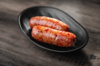 棕色木纹桌面上的盘子里放着两根烤肠