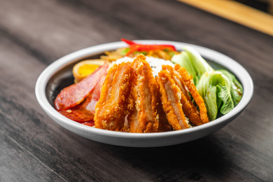 棕色木纹桌面上放着一碗砂锅炸鸡排腊肠盖饭