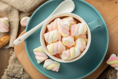 木质背景上蓝色的陶瓷杯与彩色棉花糖