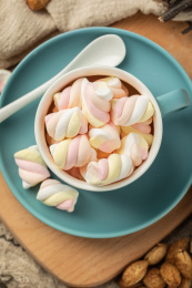 木质背景上蓝色的陶瓷杯与彩色棉花糖