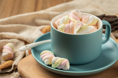 木质背景上蓝色的陶瓷杯与彩色棉花糖