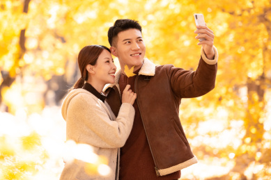 年轻的情侣正在秋天的公园里自拍