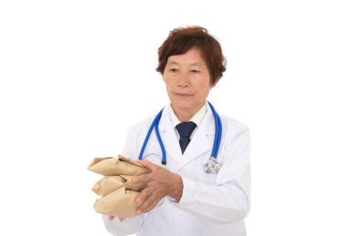 穿着白大褂的女医生手拿中药给予患者