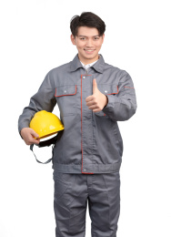   白色背景里穿着工作服手中拿着黄色安全帽的另一个手做着鼓励手势的亚洲年轻男子