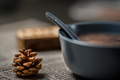 一碗充满文艺气息的红豆粥，旁边有松果，下面垫着英文报纸风格的餐巾