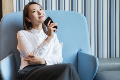 职业女性坐在沙发上拿手机微笑