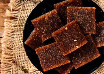 木纹背景上黑色餐具里摆放的辣片