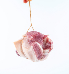 白背景上手提绳子悬吊一块新鲜猪肉