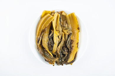 白背景上一碟腌制成金黄色酸芥菜  
