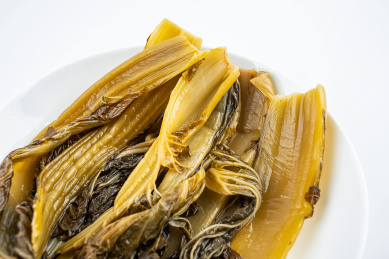 白背景上一碟腌制成金黄色酸芥菜  