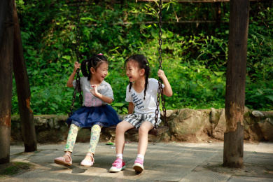 两个小女孩开心的坐在秋千上