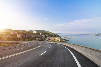 日出时分一条从海岛渔村前斜向穿过的高架柏油路