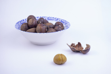 白色背景中的瓷碗里放着板栗