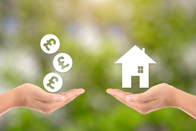 一只手托着虚拟的英镑硬币和另一只手托着虚拟的小房子进行交易