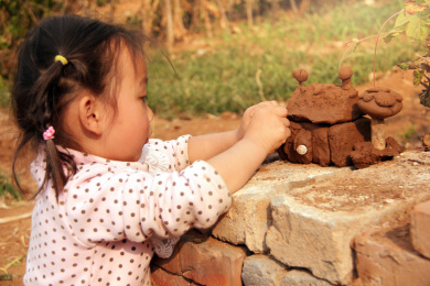 在地上玩泥巴捏泥塑的小女孩