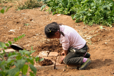 在户外玩泥巴捏泥塑的小女孩