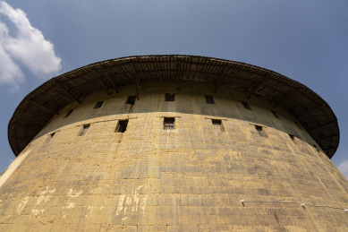 蓝天白云下仰拍的圆形土楼外墙及屋顶，中国福建永定