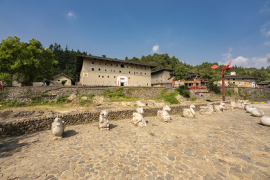 石雕的十二生肖像及河对岸的方形土楼，中国福建永定