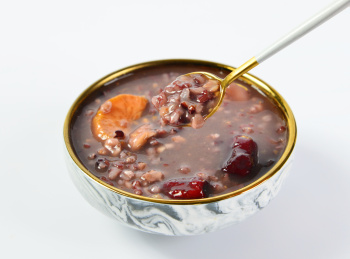 浅色背景上餐具里摆放的红枣山药粥