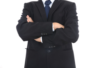 穿着黑色西装的成功人士抱着胳膊站在白背景前