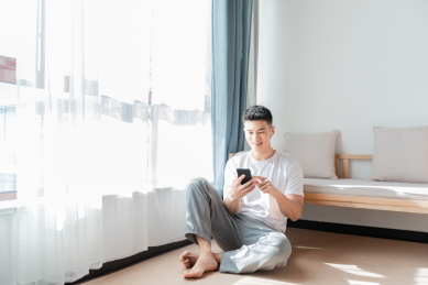 男子在家中地上坐着用手机
