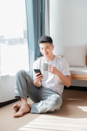 男子在家中地上坐着用手机