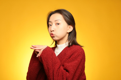 在黄色背景前模仿小老鼠的可爱女孩