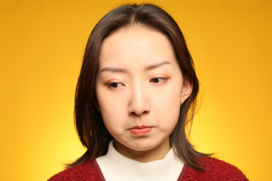 站在黄色背景前表情十分难过的中国女孩看向一旁