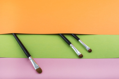 不同尺寸用途的化妆刷放在彩色的背景纸上。