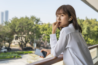 站在室外栏杆边使用智能手机的商务女青年