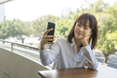 坐在室外栏杆边使用智能手机的商务女青年