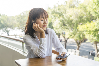 坐在室外栏杆边使用智能手机的商务女青年