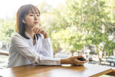 坐在室外使用智能手机听音乐的商务女青年