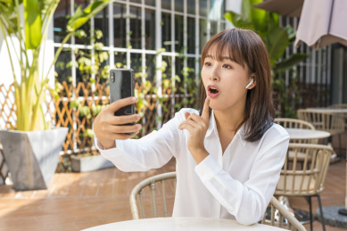坐在室外咖啡桌前视频聊天的商务女青年