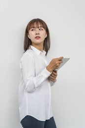 白背景墙前使用平板电脑的商务女青年