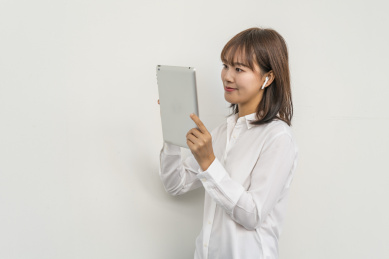 白背景墙前使用平板电脑的商务女青年