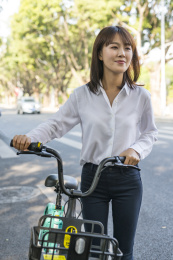 在马路边使用共享单车的商务女青年