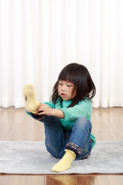 坐在地上自己穿袜子的小女孩