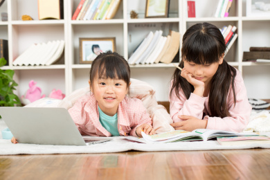 趴在地上看书写作业的两个小女孩