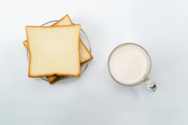 棚拍室内桌面上的玻璃杯牛奶面包片